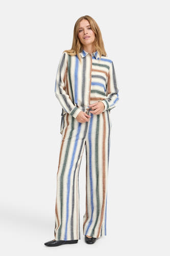 Multikleurige broek van PULZ met verticale strepen en wijde pijpen, gedragen met een bijpassende gestreepte blouse.
