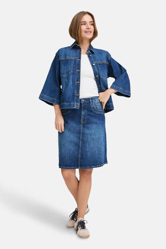 Donkerblauwe jeansjas van PULZ, gedragen over een wit shirt en een jeansrok.
