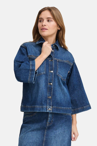 Jeansjas van donkerblauw denim van PULZ, met zilverkleurige knopen en borstzakken, gecombineerd met een jeans rok.
