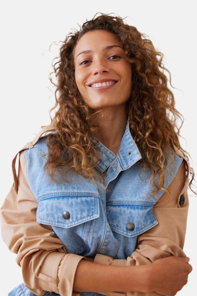 Jeansjas in lichtblauw denim van PULZ, met bruine mouwen en borstzakken, gekruiste armen.
