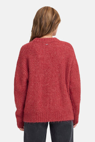 Rode trui met ronde hals van PULZ, met zichtbaar labeldetail aan de achterkant en gedragen met een zwarte broek.
