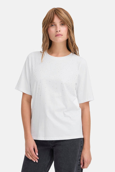 Wit T-shirt van PULZ met strass steentjes op de voorkant, gecombineerd met een donkere jeans.
