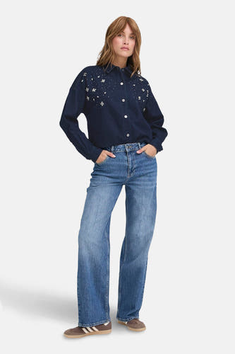 T-shirt en jeans de denim bleu foncé PULZ, orné de fleurs et de points, porté avec des jeans bleus et des baskets brunes.