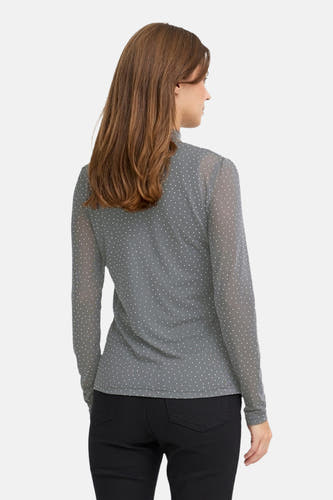 Grijs shirt van PULZ met lange mouwen en witte stippen, gecombineerd met een zwarte broek, achteraanzicht.
