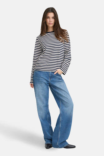 Blauw gestreept T-shirt met lange mouwen van PULZ, gedragen met wijde jeans en zwarte schoenen.

