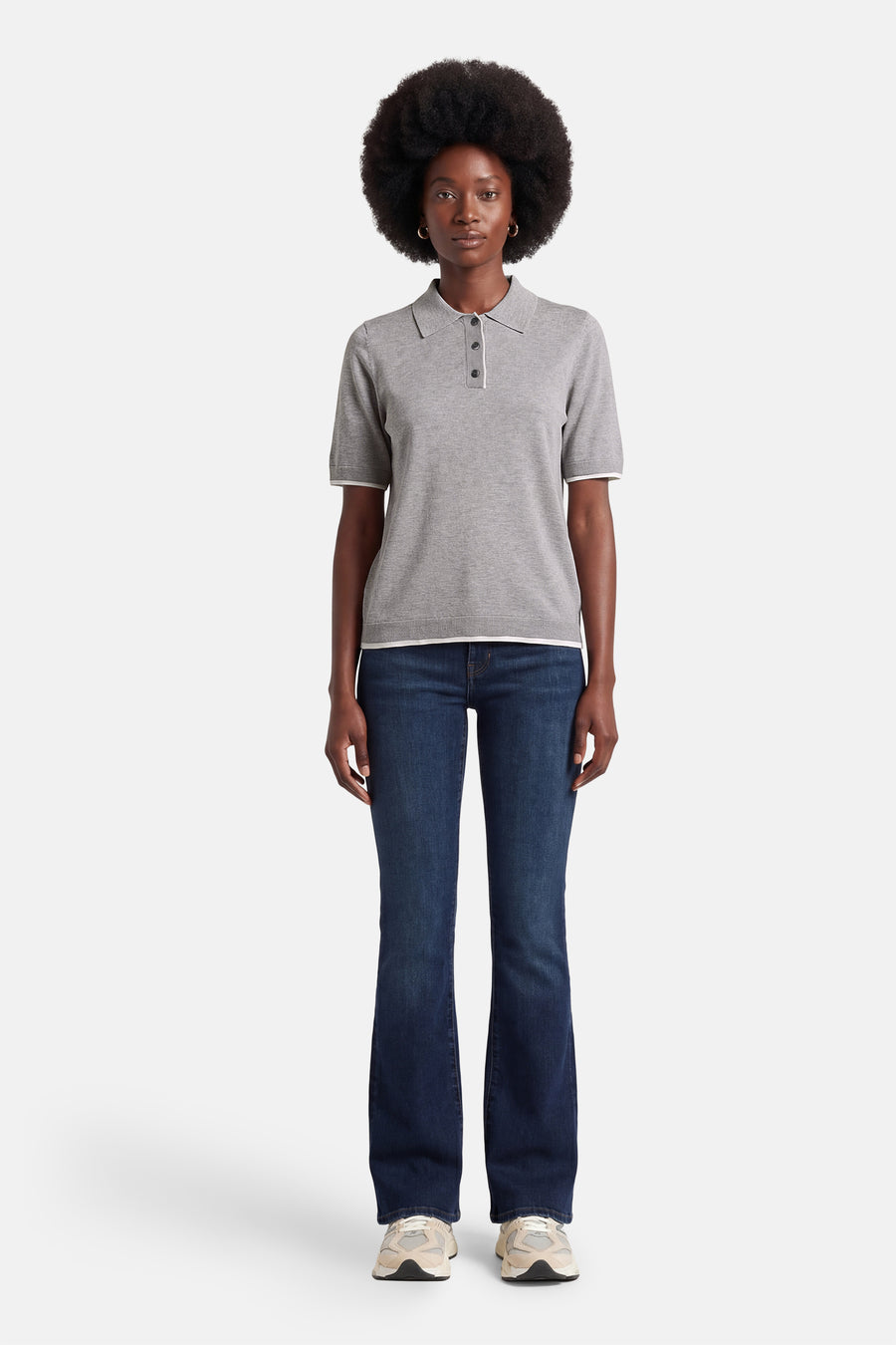 Grijze trui met ronde hals van PULZ, gecombineerd met donkerblauwe jeans en crèmekleurige sneakers.