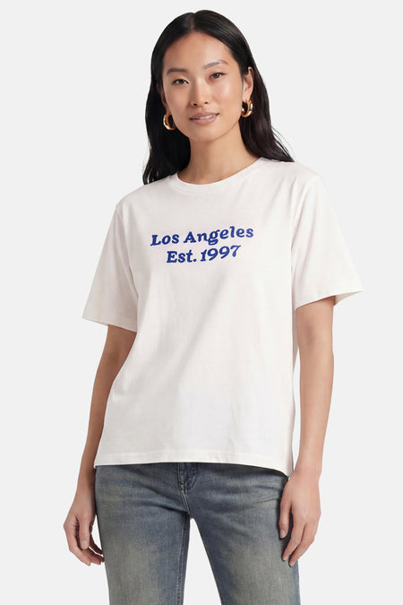 Wit T-shirt van PULZ met blauwe 'Los Angeles Est. 1997' opdruk, gedragen met blauwe jeans.