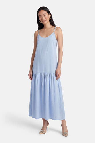 Robe bleue sans manches de PULZ, avec fines bretelles et jupe évasée, portée avec des escarpins beiges.