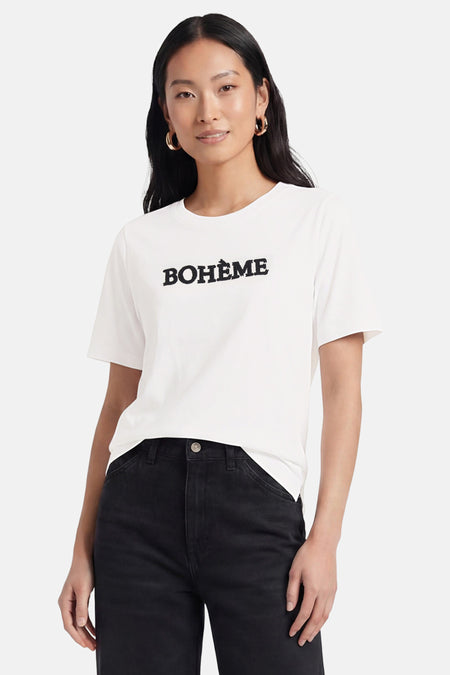 Wit T-shirt van PULZ met de zwarte tekst "BOHÈME", gedragen door een vrouw in zwarte jeans.