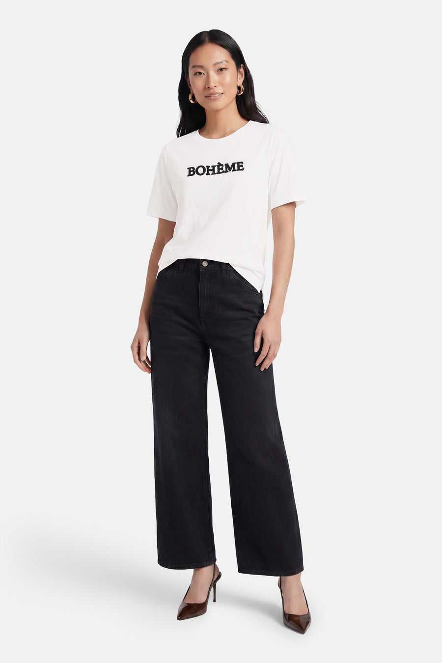 Wit T-shirt van PULZ met "BOHÈME" in zwart op de voorkant, gedragen met een zwarte wide-leg jeans en bruine puntige hakken.