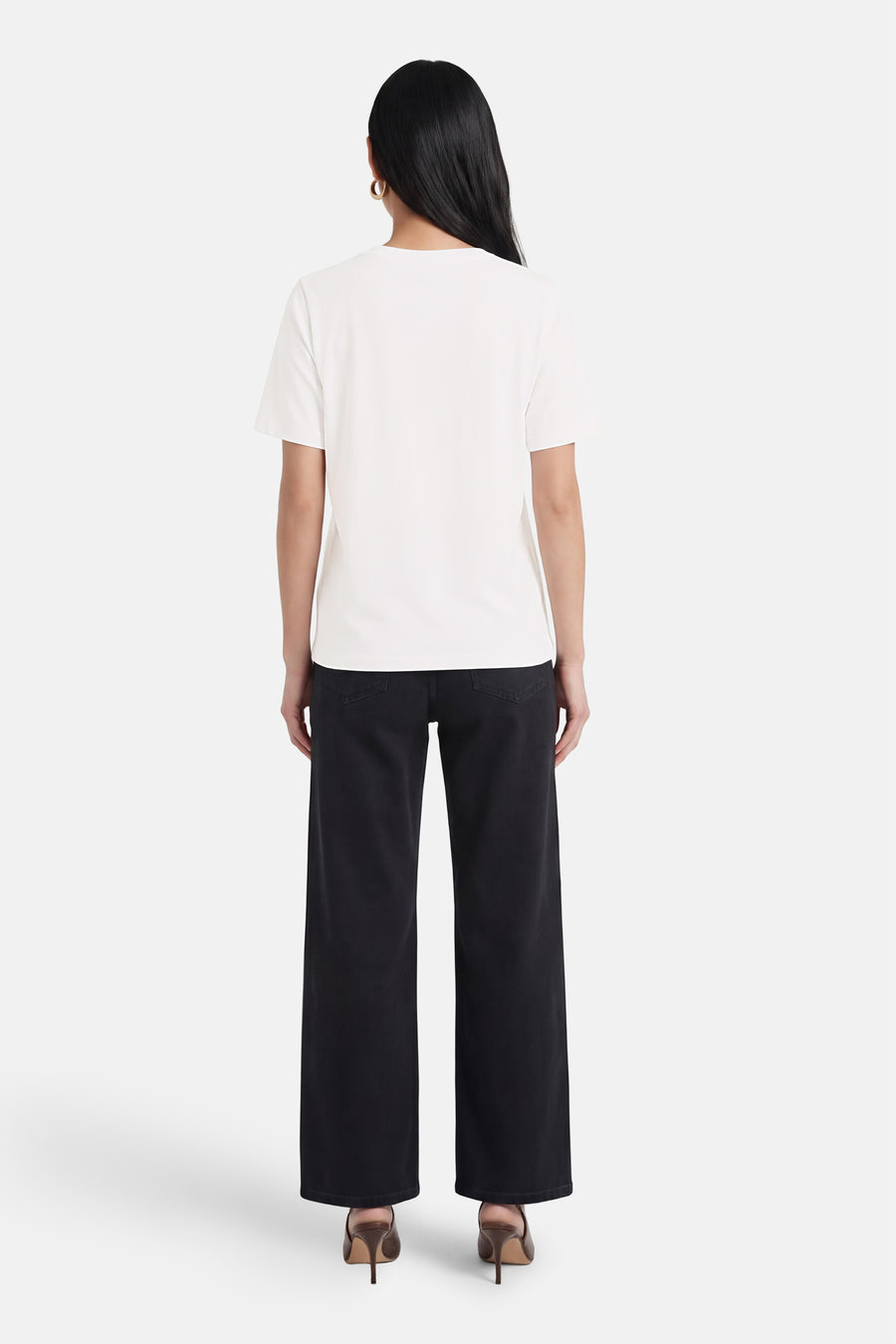 Wit T-shirt van PULZ, van achteren gezien op een model met zwarte wijde broek en bruine hakken.