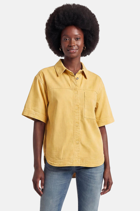 Geel jeanshemd van PULZ met kraag, korte mouwen en borstzak, gedragen door model met afro en gouden oorringen.