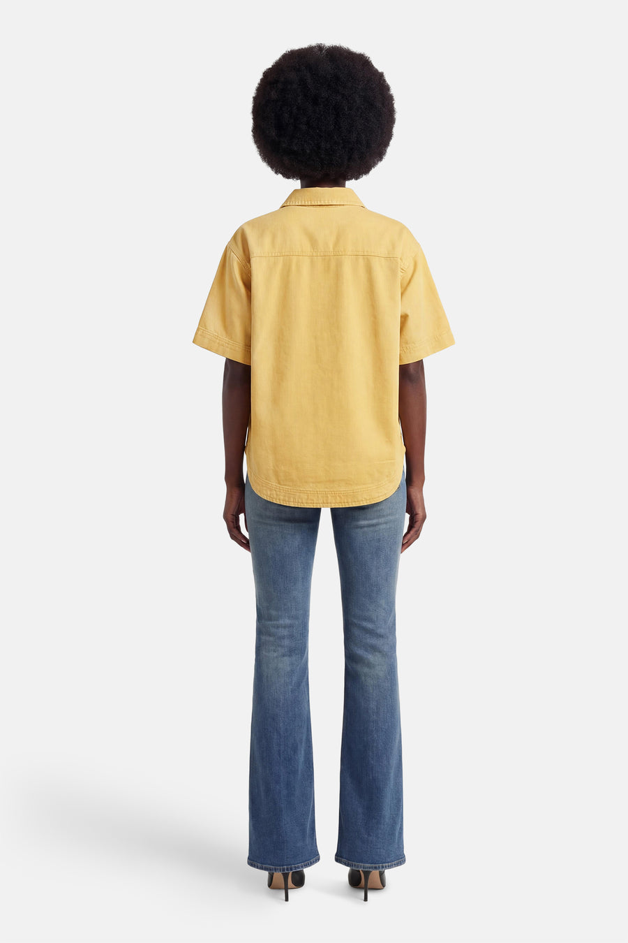 Geel jeanshemd van PULZ met korte mouwen, van achteren gezien op een model in blauwe jeans en zwarte hakken.