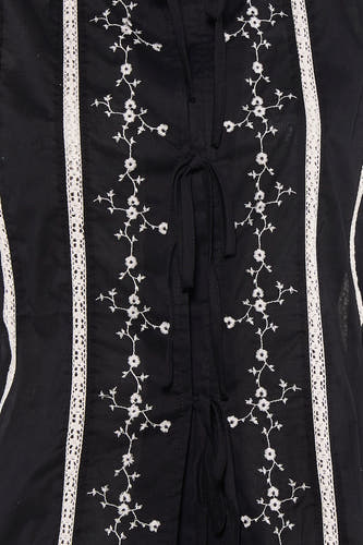 Zwarte mouwloze blouse van PULZ met witte bloemen borduurwerk en kant details, close-up van voorkant