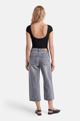 Grijze denim bermuda van PULZ, gedragen door een vrouw vanaf de achterkant met een zwart topje en zwarte platte schoenen.
