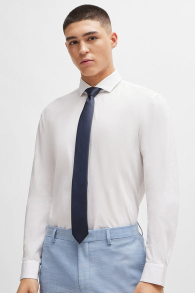 Blauwe das van HUGO, gedragen met een wit overhemd en lichtblauwe pantalon.
