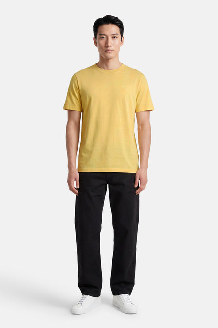 Geel T-shirt met korte mouwen van HUGO, voorzien van een kleine witte logoprint op de borst en gedragen door een man in zwarte broek en witte sneakers.
