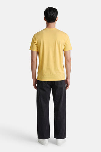 Geel T-shirt met korte mouwen van HUGO, achterkant, gedragen door een man met een zwarte jeans en witte sneakers.