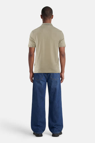Polo verte HUGO, vue de dos par un homme, combinée avec un jean ample et des baskets.