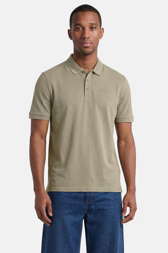 Polo verte HUGO verte de couleur verte avec deux boutons, un logo brodé, portée par un homme en jean.