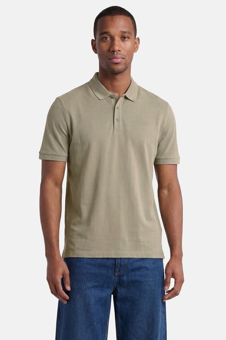 Groene polo van HUGO met twee knopen, een geborduurd logo, gedragen door een man in een spijkerbroek.