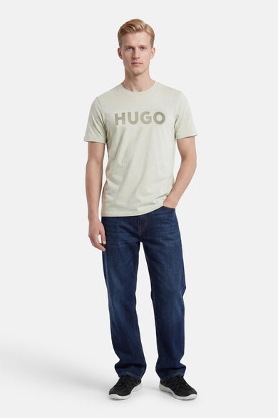 Groen T-shirt van HUGO met logo op de borst, gedragen door een man met donkere jeans en sneakers.