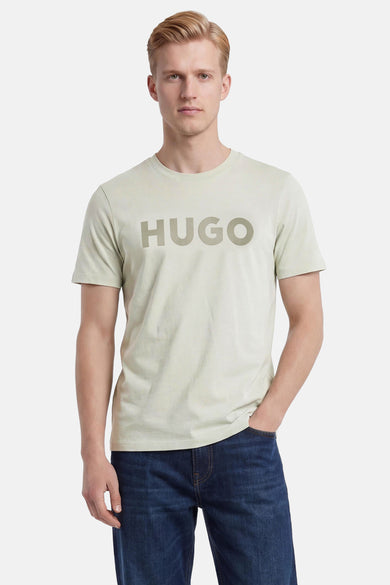 Lichtgroen T-shirt van HUGO met groot logo op de borst, gedragen door een man in donkerblauwe jeans.