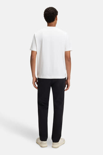 Wit T-shirt met korte mouwen van HUGO BOSS ORANGE, gezien vanaf de achterkant, gecombineerd met een zwarte broek en crèmekleurige schoenen.