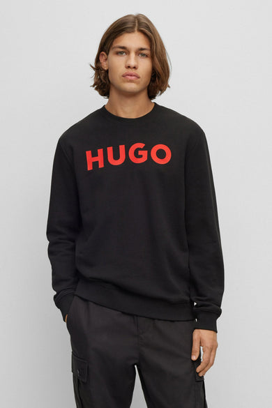 Zwarte sweater van HUGO, met rode merknaam op de borst, gecombineerd met een zwarte cargo broek.
