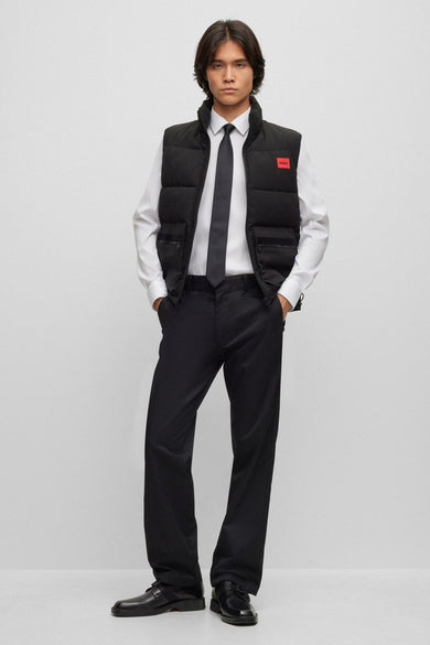 Wit overhemd met lange mouwen van HUGO, gedragen met een zwarte bodywarmer en stropdas.