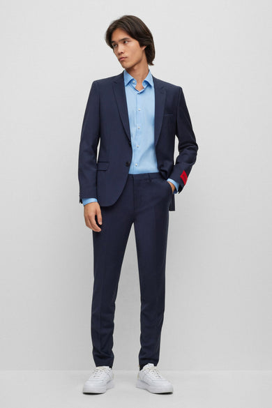 Blauw overhemd met lange mouwen van HUGO, gedragen met een marineblauw pak en witte sneakers.
