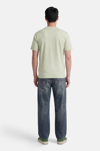 T-shirt vert à manches courtes de HUGO, dos d'un homme avec un jean foncé et des baskets vertes.