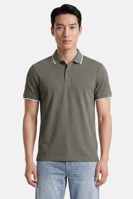 Kakikleurige polo van HUGO BOSS ORANGE met klassieke kraag, twee knopen, witte biezen en een ton-sur-ton BOSS-patch op de borst.