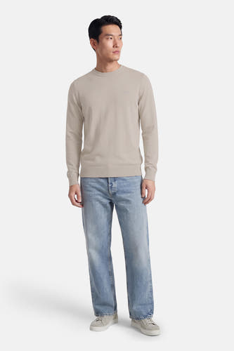 Pull gris à col rond de HUGO BOSS ORANGE, porté avec un jean bleu et des baskets en daim.