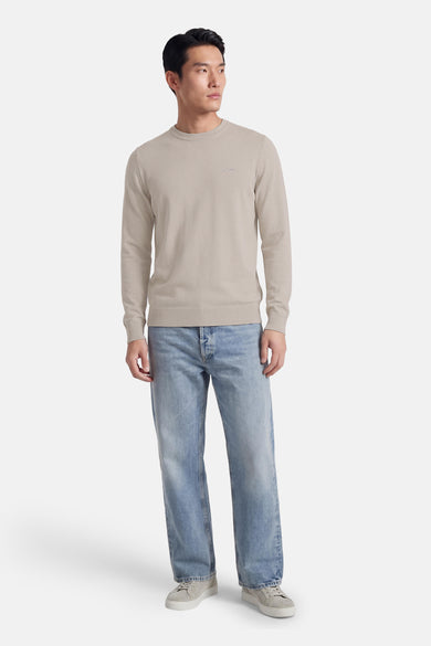 Pull gris à col rond de HUGO BOSS ORANGE, porté avec un jean bleu et des baskets en daim.