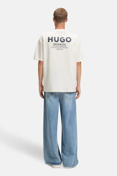 Ecru T-shirt met korte mouwen van HUGO BLUE, met tekstlogo op de achterkant en gecombineerd met wijde jeans.
