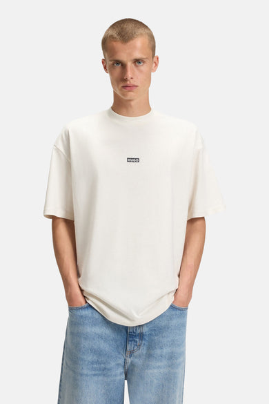 Ecru T-shirt met korte mouwen van HUGO BLUE, gedragen met een jeansbroek met lichte wassing.
