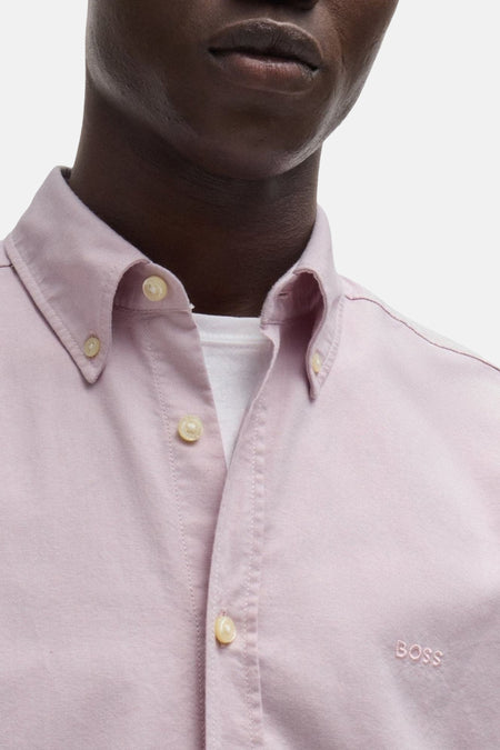 Roze lange mouwen overhemd van HUGO BOSS ORANGE, close-up met knopen en geborduurd logo, gestoffeerd katoen, model draagt wit onderhemd