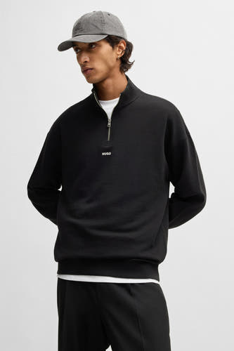 Pull-over noir avec fermeture éclair de HUGO, porté avec un chapeau gris à logo.