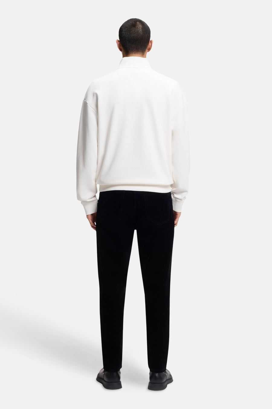 Witte sweater (ronde hals) van HUGO, gezien van achteren, gecombineerd met een zwarte broek en zwarte schoenen.
