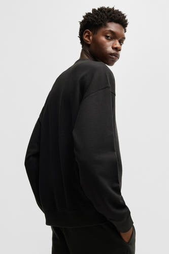 Zwarte sweater met ronde hals van HUGO, gezien van de achterkant, met donkere broek.
