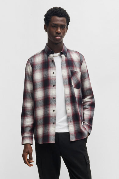 Rood overhemd met lange mouwen van HUGO, met ruitpatroon, gedragen over een wit T-shirt en een zwarte broek.
