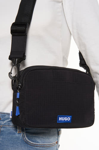 Zwarte schoudertas van HUGO BLUE, met verstelbare band en blauwe accenten op de rits.