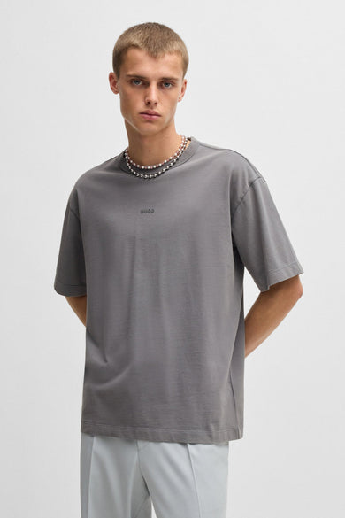 Grijs T-shirt met korte mouwen van HUGO, gedragen met een zilverkleurige ketting tegen een witte achtergrond.
