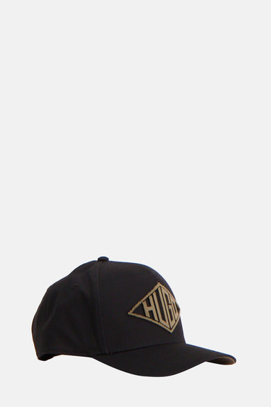 Zwarte pet van HUGO, met logo badge op de voorkant, in zij-aanzicht.