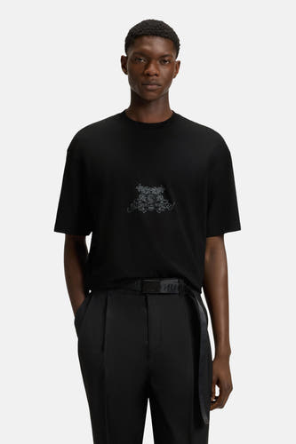 T-shirt noir à manches courtes de HUGO, avec une impression décorative sur la poitrine, associé à un pantalon noir et une ceinture.