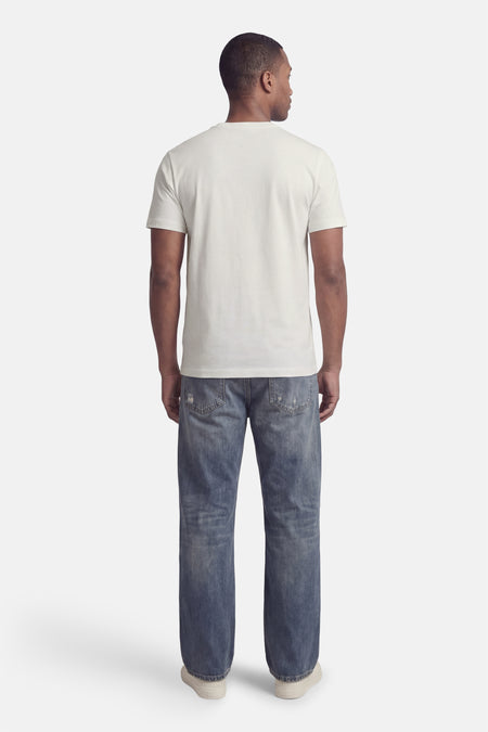 T-shirt blanc à manches courtes de HUGO, vu de dos, porté avec un jean bleu et des chaussures claires.