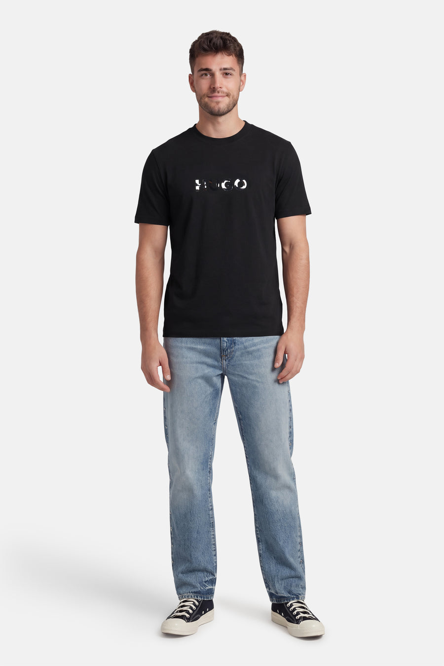 Zwart T-shirt met korte mouwen van HUGO, gedragen met blauwe jeans en zwarte sneakers.