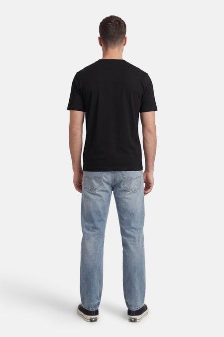 T-shirt noir à manches courtes de HUGO, vu de dos, associé à un jean bleu et des baskets foncées.