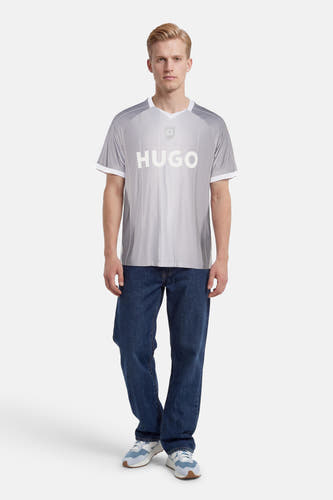 Grijs T-shirt met diagonale strepen van HUGO, met wit logo, embleem, V-hals en witte boorden, gedragen door een man.